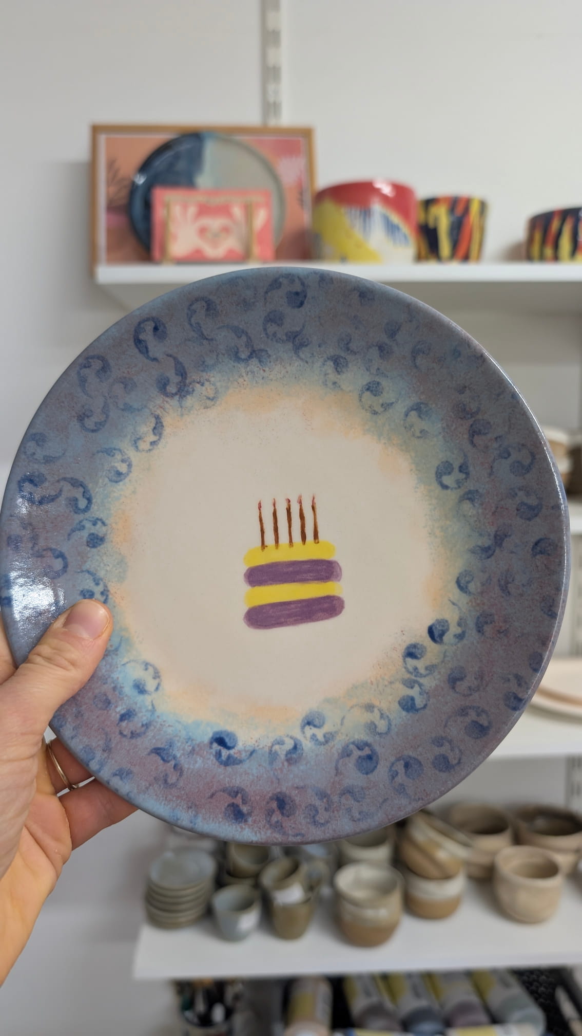 Talerz urodzinowy z ręcznie malowanym tortem ze świeczkami i niebieskim cieniowanym wzorem na brzegu.