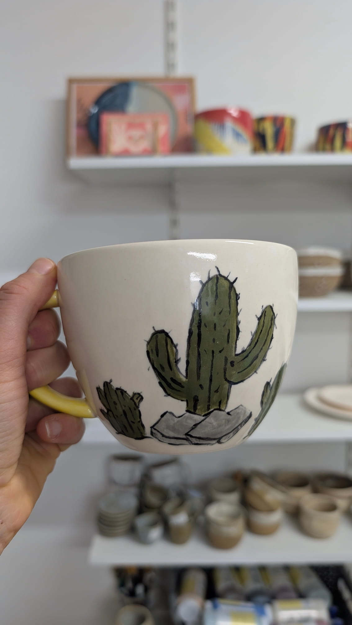 Duży jasny kubek ceramiczny z ręcznie malowanym zielonym kaktusem w doniczce – motyw roślinny.